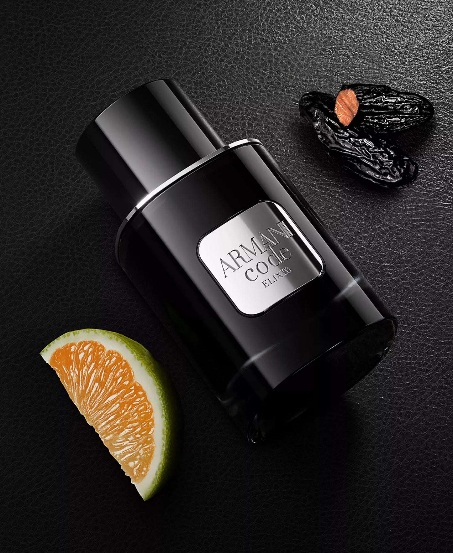 Black Armani Code perfume bottle with orange slice and dark fruit on a black background