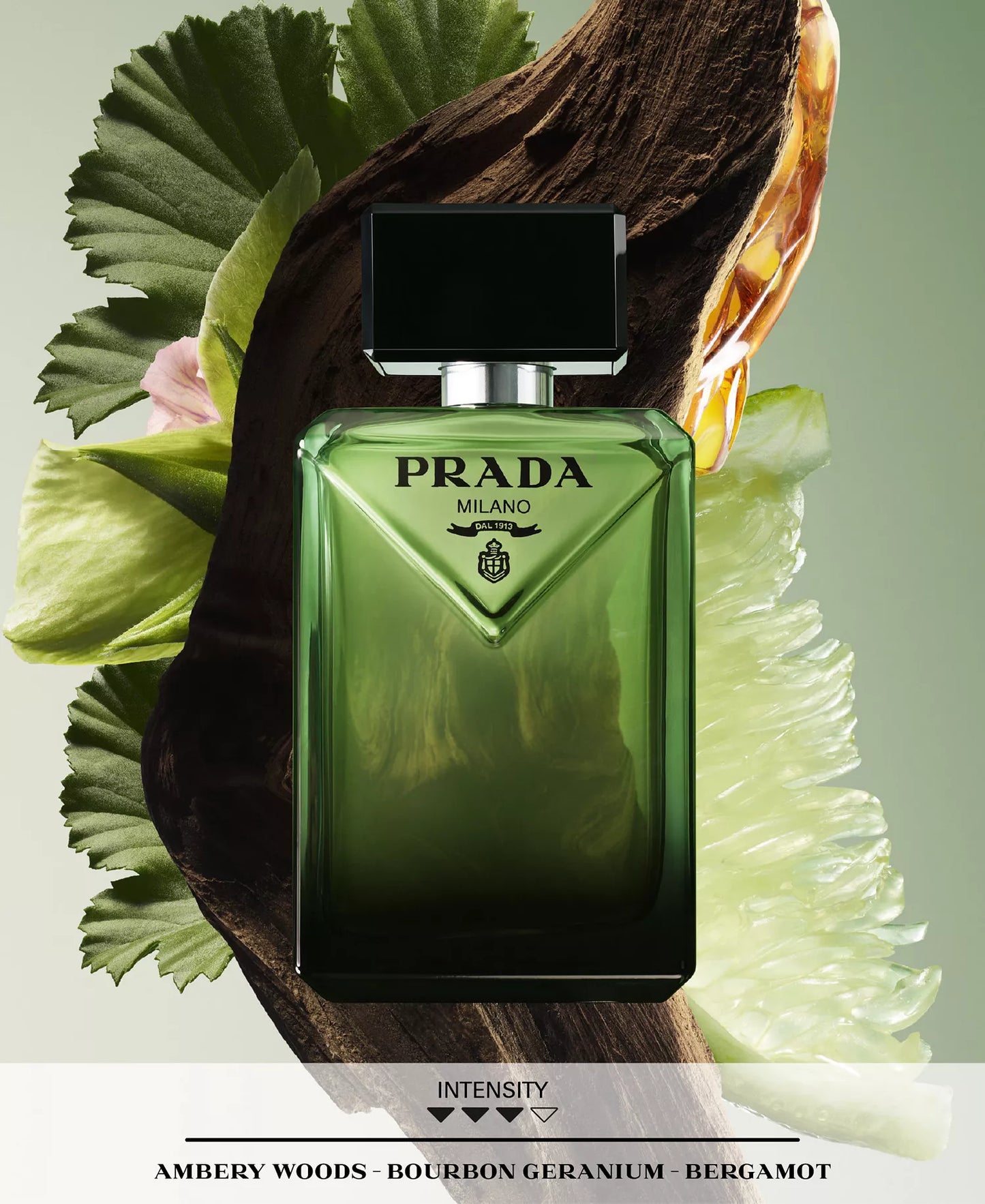 Green Prada Milano perfume bottle on a decorative background with leaves and flowers.