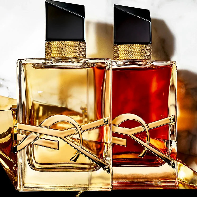 Two gold and black perfume bottles with a blurred background