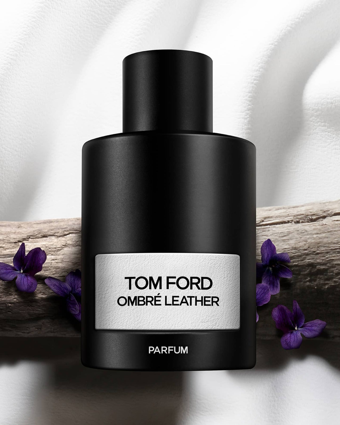 Tom Ford Ombre Leather parfum bottle with purple flowers on a white background