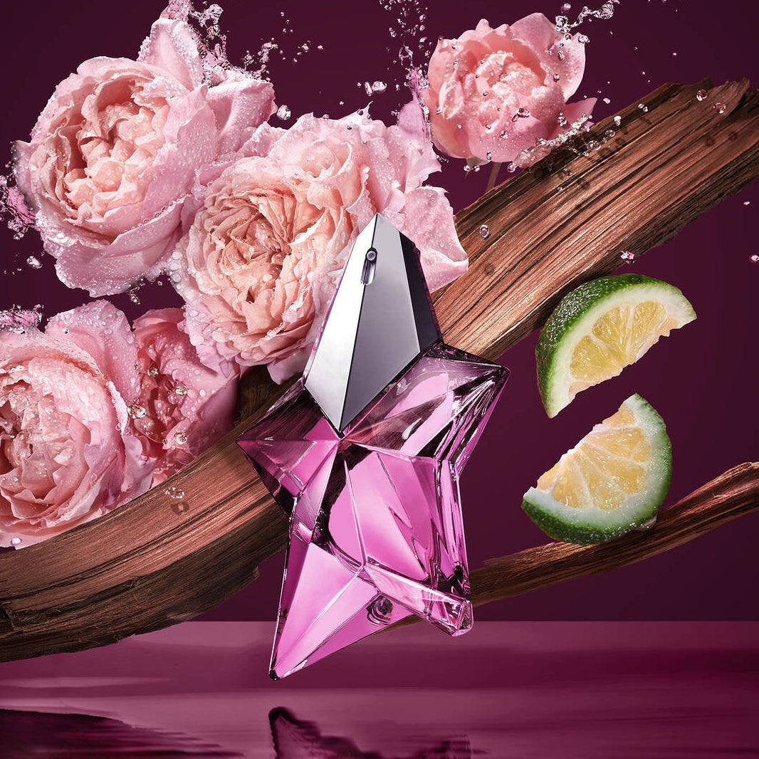 Pink perfume bottle with flowers, lime slices, and wood on a purple background