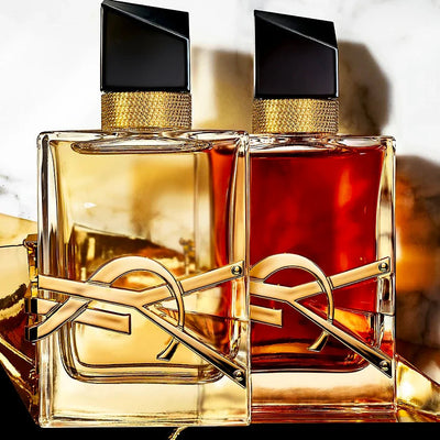 Two gold and black perfume bottles with a blurred background