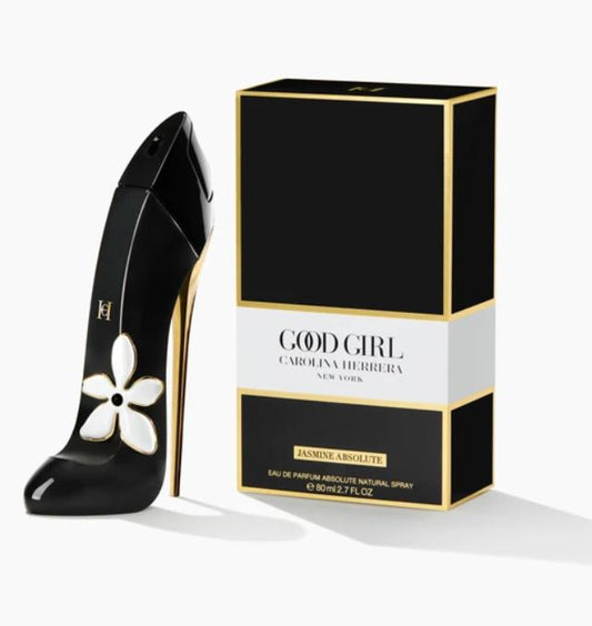 Black high-heeled shoe with white flower design next to Carolina Herrera Good Girl perfume box.