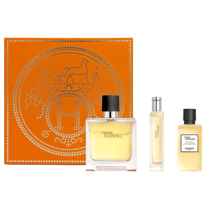 Hermès fragrance gift set on a white background, featuring an orange box with a silver horse-and-coin emblem, a large rectangular Terre d'Hermès perfume bottle, a slim spray bottle, and a smaller rectangular bottle labeled Hermès.