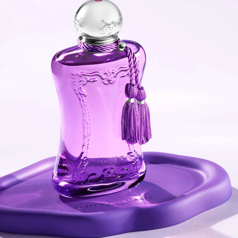 Purple perfume bottle with tassels on a matching purple platform